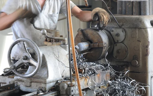 Азиатский рабочий в грязной рубашке манипулирует токарным станком — стоковое фото