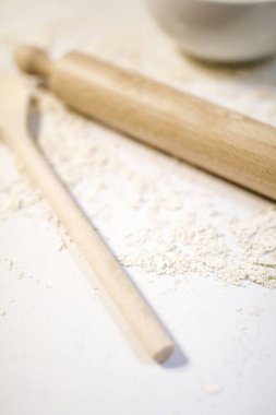 wooden rolling pin and spoon on table covered by flour