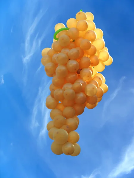 Vliegende ballonnen in de vorm van druiven over blauwe hemel — Stockfoto