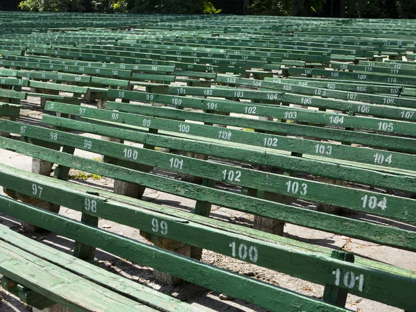 Řady jednoduchých zelené sedadel u prázdné venkovní scéna — Stock fotografie
