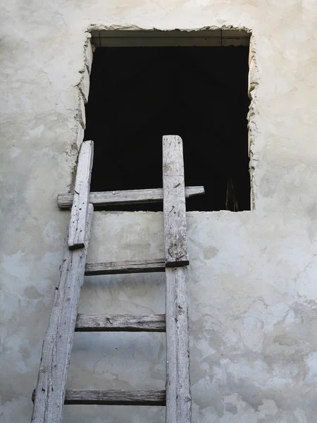 Oude houten ladder naar venster over de muur — Stockfoto