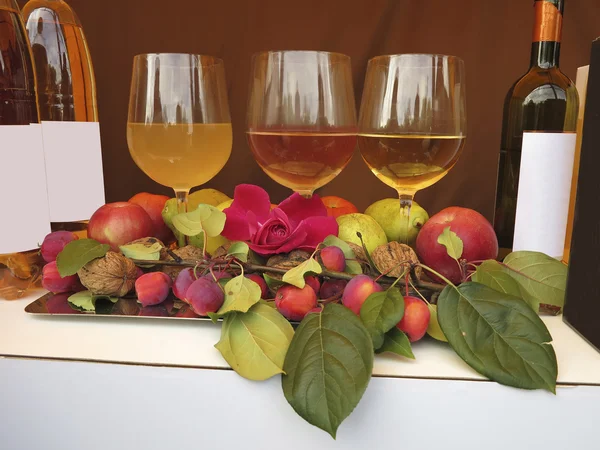 Tres copas de vino botellas de manzanas rosadas y nueces composición —  Fotos de Stock