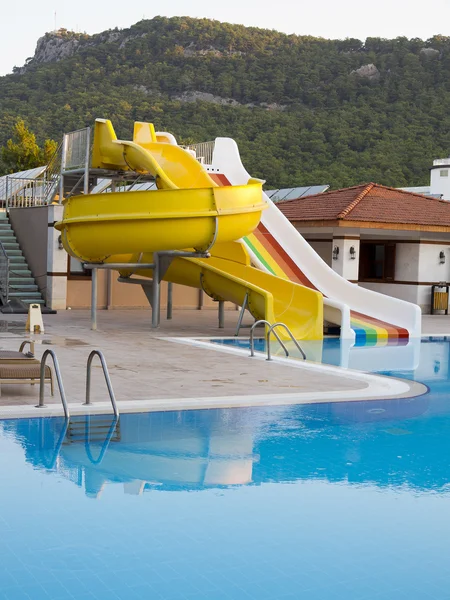 Colorful waterslides in water park pool and mountain — Stock Photo, Image