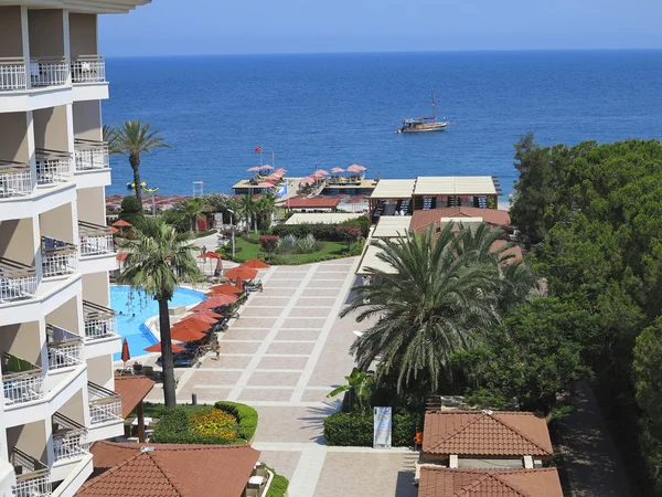 一家豪华酒店、 棕榈树、 游泳池和一艘船在海上 — 图库照片