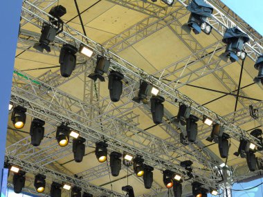 Spotlight devices in a row on  rigging steel trusses, installation of professional stage concert equipment.