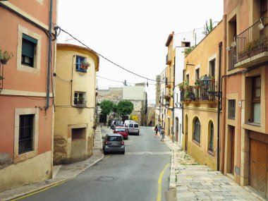 TARRAA, SPAIN - 06.07.2022: Ortaçağ şehrinin eski caddesi (UNESCO 'nun Dünya Mirası Alanı) ve onun Romansı binaları güneşli bir günde. Katalonya, İspanya.