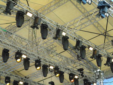 Spotlight devices in a row on  rigging steel trusses, installation of professional stage concert equipment.