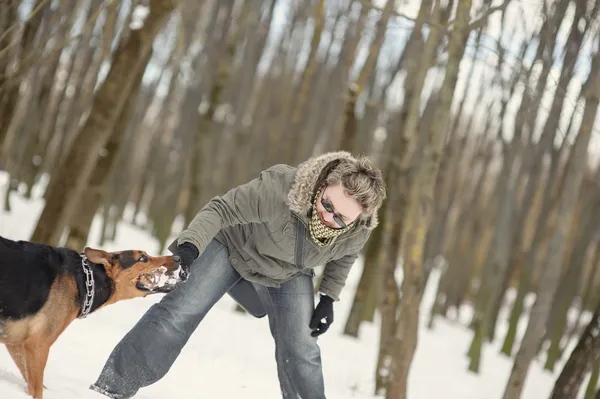 Дівчина грає з собакою на снігу — стокове фото