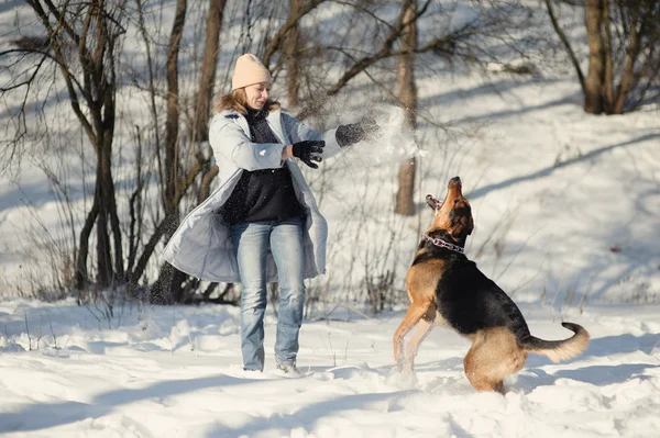 Meisje met hond spelen in de sneeuw — Stockfoto