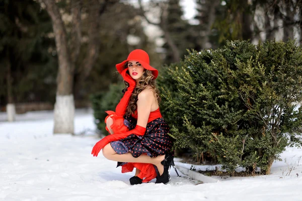 Приваблива дівчина в червоній шапці на відкритому повітрі на снігу — стокове фото