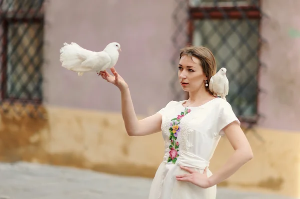Jolie fille avec colombe dans la main posant sur une rue de la ville — Photo