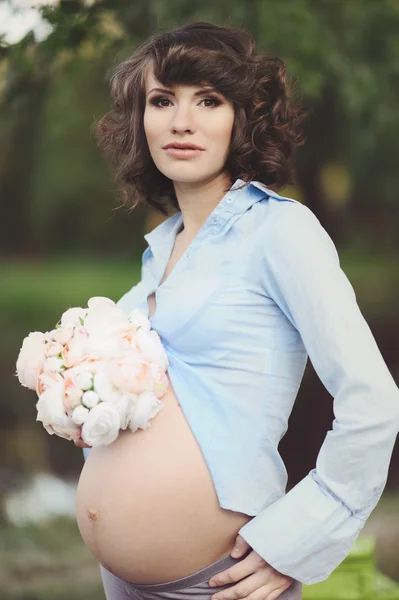 Glückliche junge schwangere Frau, die ihren Bauch berührt — Stockfoto