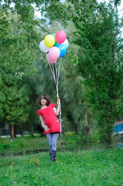 Счастливая беременная женщина с воздушными шарами в руках — стоковое фото