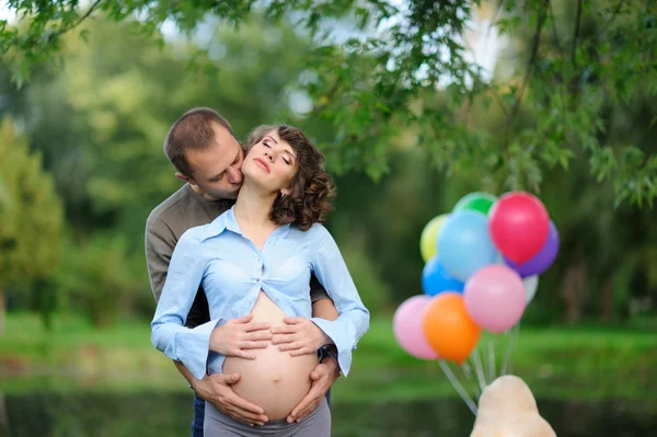 Счастливые будущие родители на прогулке в летнем парке — стоковое фото