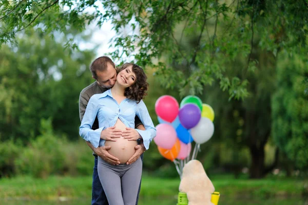 Счастливые будущие родители на прогулке в летнем парке — стоковое фото