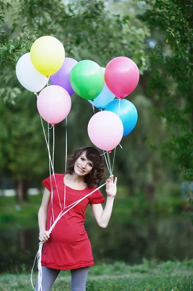 Glückliche junge schwangere Frau mit Luftballons in den Händen — Stockfoto