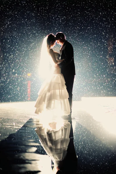 Noiva e noivo beijando sob chuva durante a noite — Fotografia de Stock