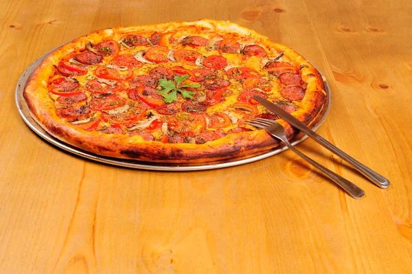 意大利辣香肠比萨饼用刀子和叉子木制的桌子上 — 图库照片