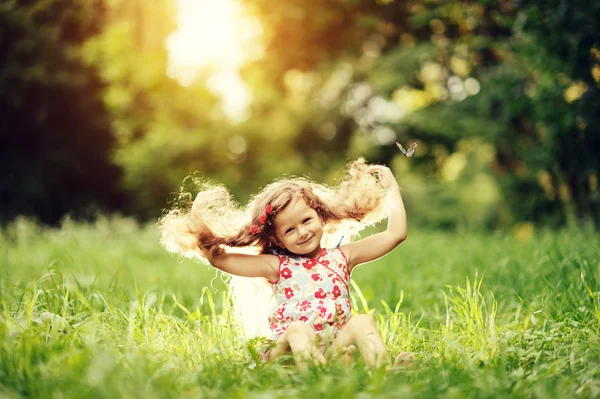 Usmíval se holčičky sedící na zelené trávě — Stock fotografie