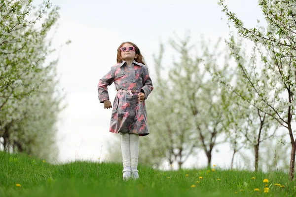 Kleines hübsches Mädchen springt in den grünen Garten — Stockfoto
