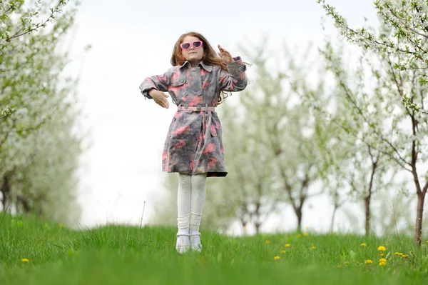 Kleines hübsches Mädchen springt in den grünen Garten — Stockfoto