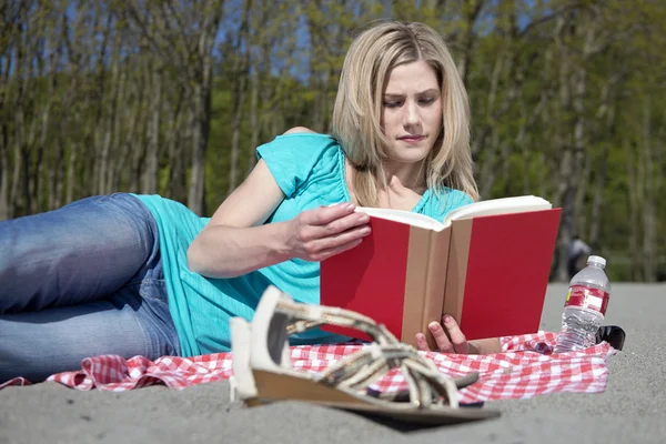 Çekici bir kadın bir plajda bir kitap okuma — Stok fotoğraf