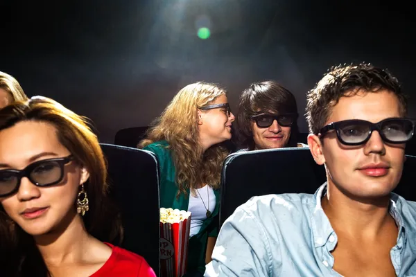 Женщина шепчет в ухо бойфренду в кинотеатре — стоковое фото