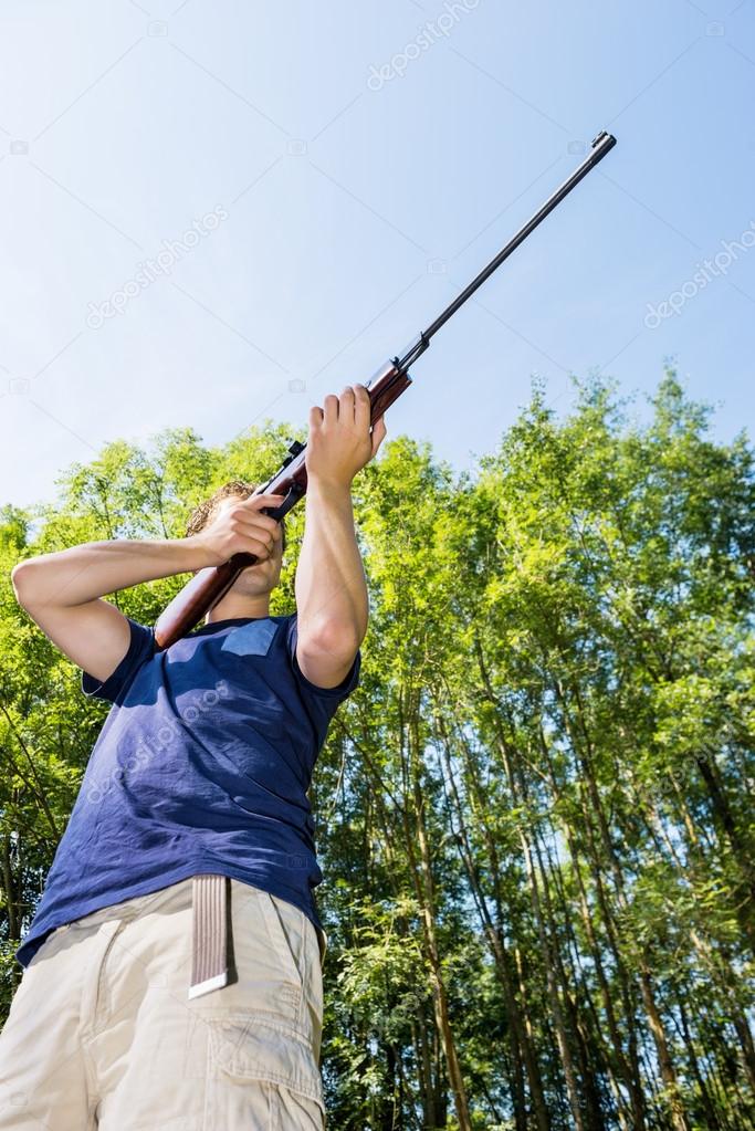 Man With Rifle Hunting In Forest