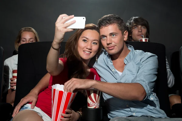 Pareja viendo películas en el cine y fotografiándose a sí mismos — Foto de Stock