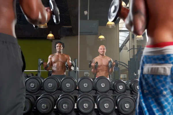 Reflejo espejo de dos hombres ejercitándose en el gimnasio — Foto de Stock