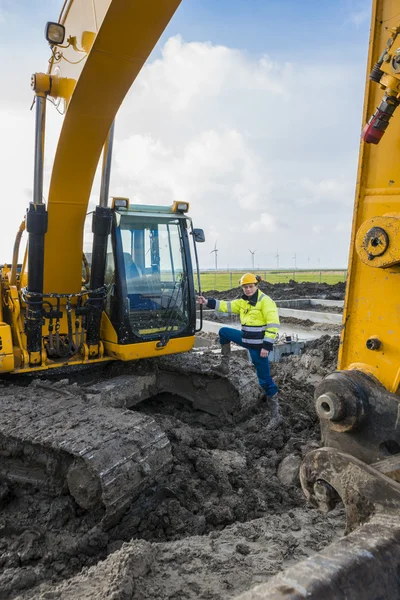 Trabajador de la construcción de pie con orgullo junto a su excavadora — Foto de Stock