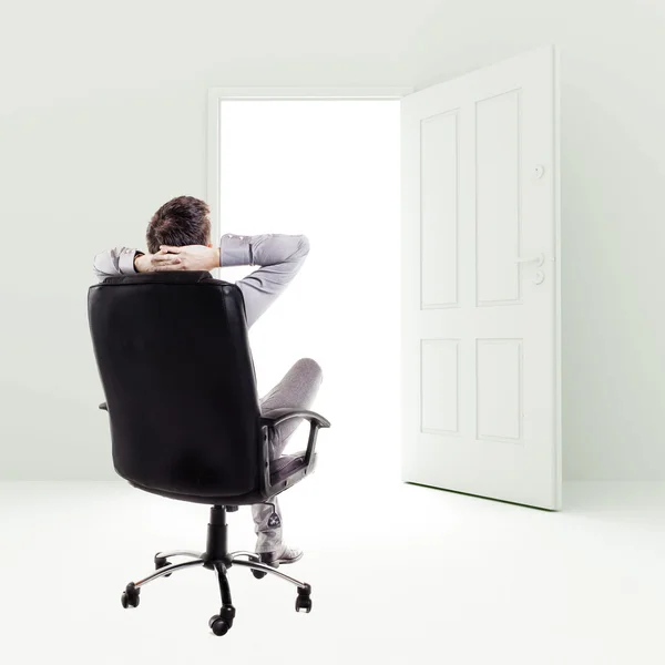 Uomo d'affari su una sedia davanti alla porta aperta — Foto Stock