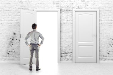 vintage beyaz duvarında açık bir kapı önünde genç iş adamı