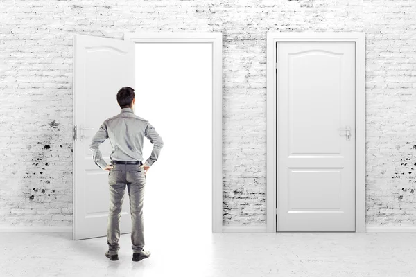 ヴィンテージ白レンガの壁に開いたドアの前の若いビジネス男 — ストック写真