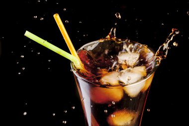 Fresh cola juice and ice cubes splash in a glass on black background