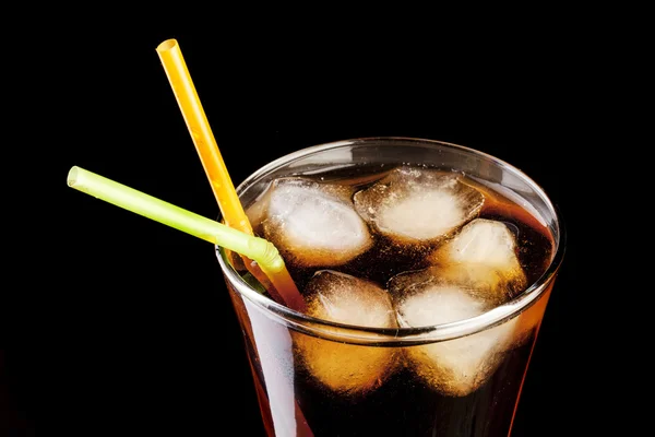 Zumo de cola fresca y cubitos de hielo salpican en un vaso sobre fondo negro —  Fotos de Stock