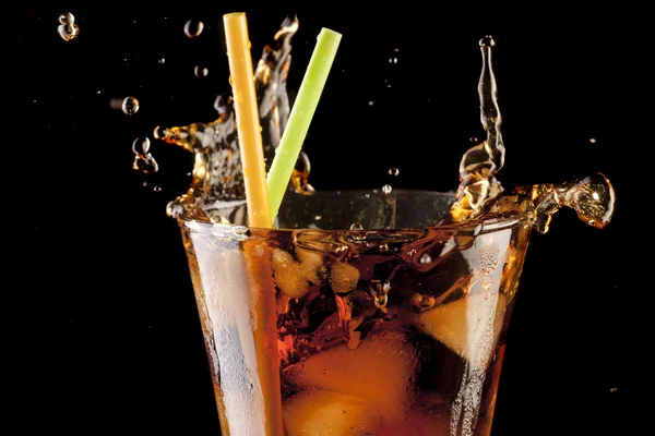 Friss cola gyümölcslé és jeges kockák splash egy üveg fekete háttér — Stock Fotó