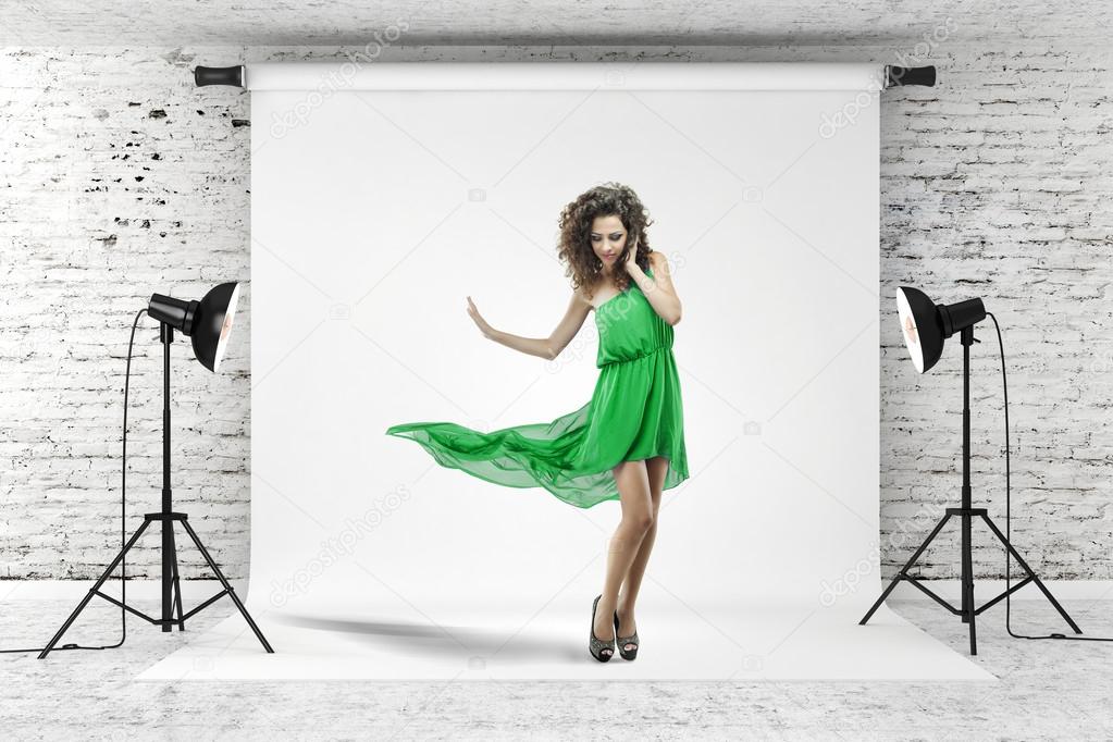 Young beautiful woman in green dress posing in studio