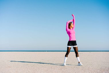 Güçlü ve formda bir kadın kumsalda çalışıyor.