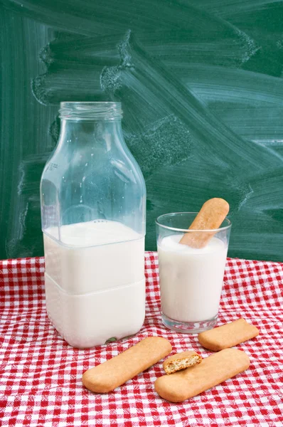 Garrafa e um copo de leite com bolos — Fotografia de Stock