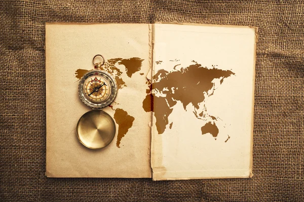 Vieux livre ouvert avec boussole et carte du monde — Photo