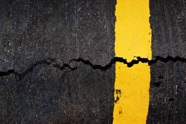 Yellow line on cracked asphalt road — Stock Photo, Image