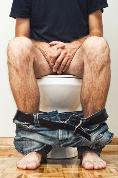 Man sitting on toilet — Stock Photo, Image