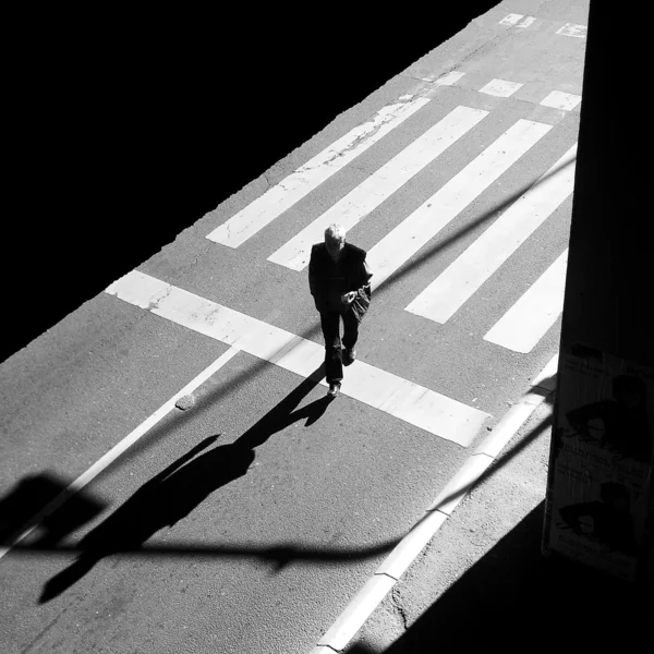 Un peatón cruzando la calle. Hombre en el cruce de cebra. Escena urbana. blanco y negro . — Foto de Stock