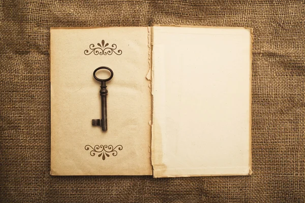 Old open book and rusty key — Stock Photo, Image