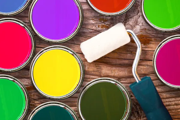 Paint roller a barevné plechovky barvy na dřevěné pozadí — Stock fotografie