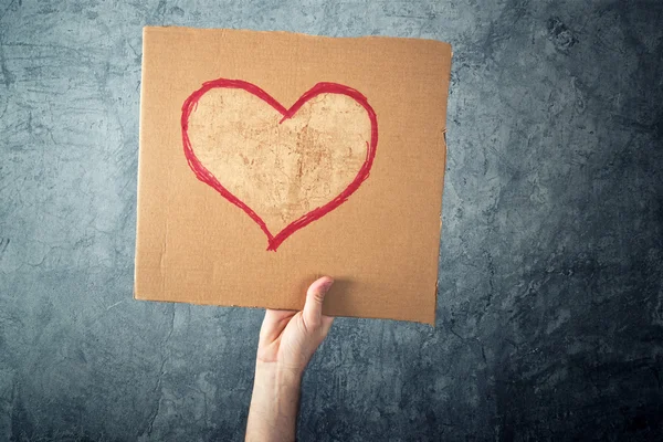 Man holding cardboard paper with heart shape drawing — Stock Photo, Image