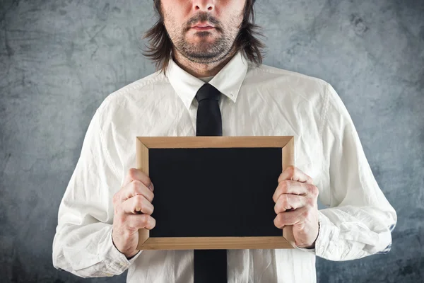 Businessman holding blank blackboard — Stock Photo, Image