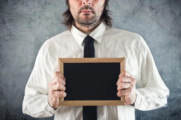 Businessman holding blank blackboard — Stock Photo, Image