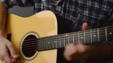 Adam akustik gitar çalıyor.
